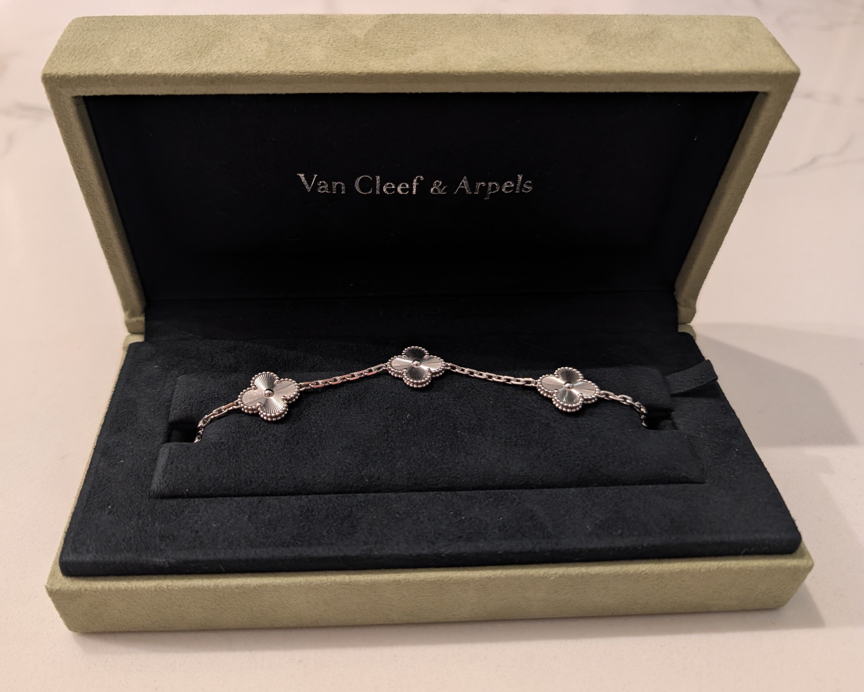 Pre-owned Van Cleef & Arpels Vintage Alhambra 5-motif bracelet in 18K white gold with guilloché finish, resting in its original green velvet presentation box.