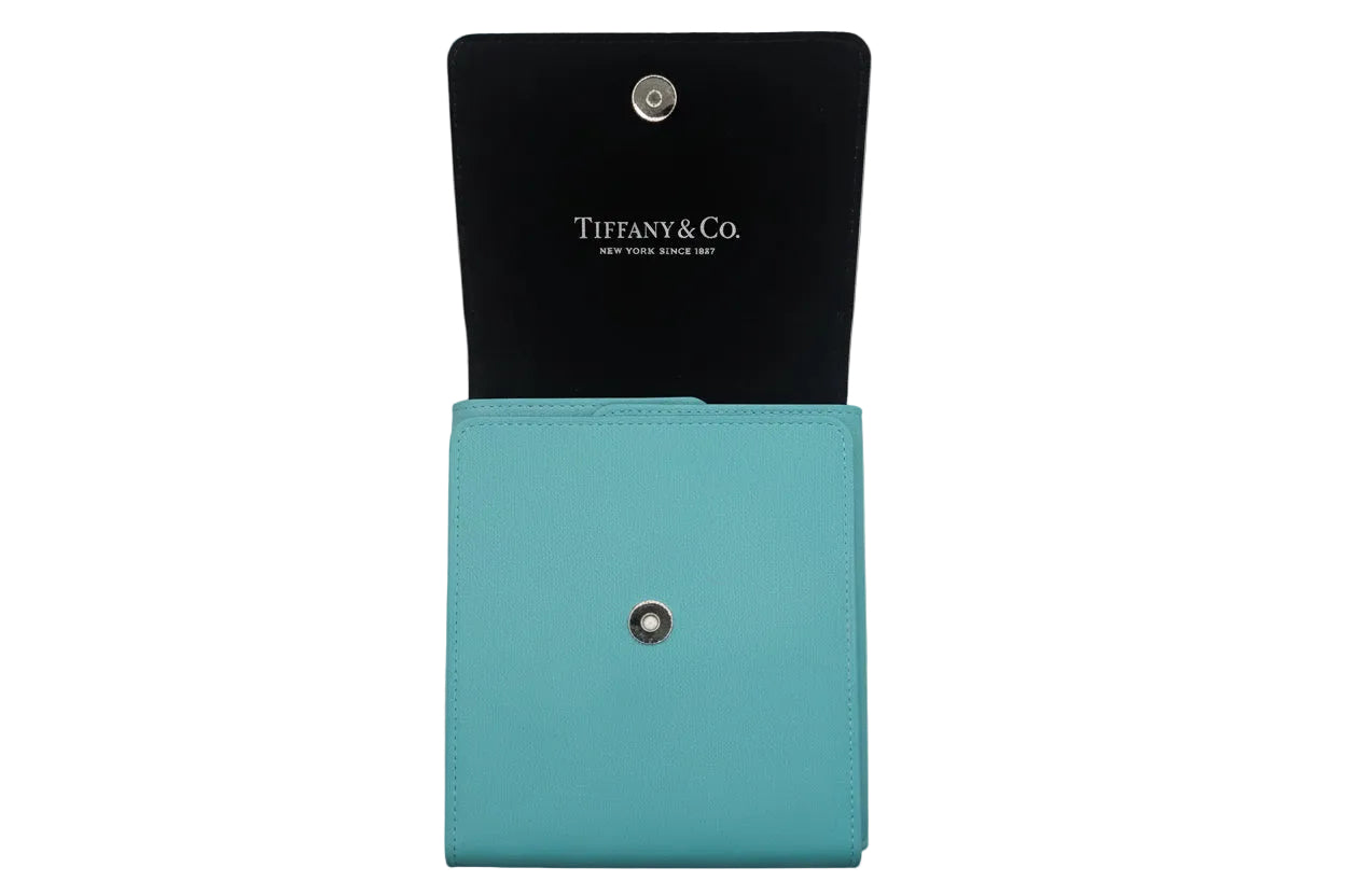 Tiffany & Co. turquoise leather wallet with black interior on a light gray background