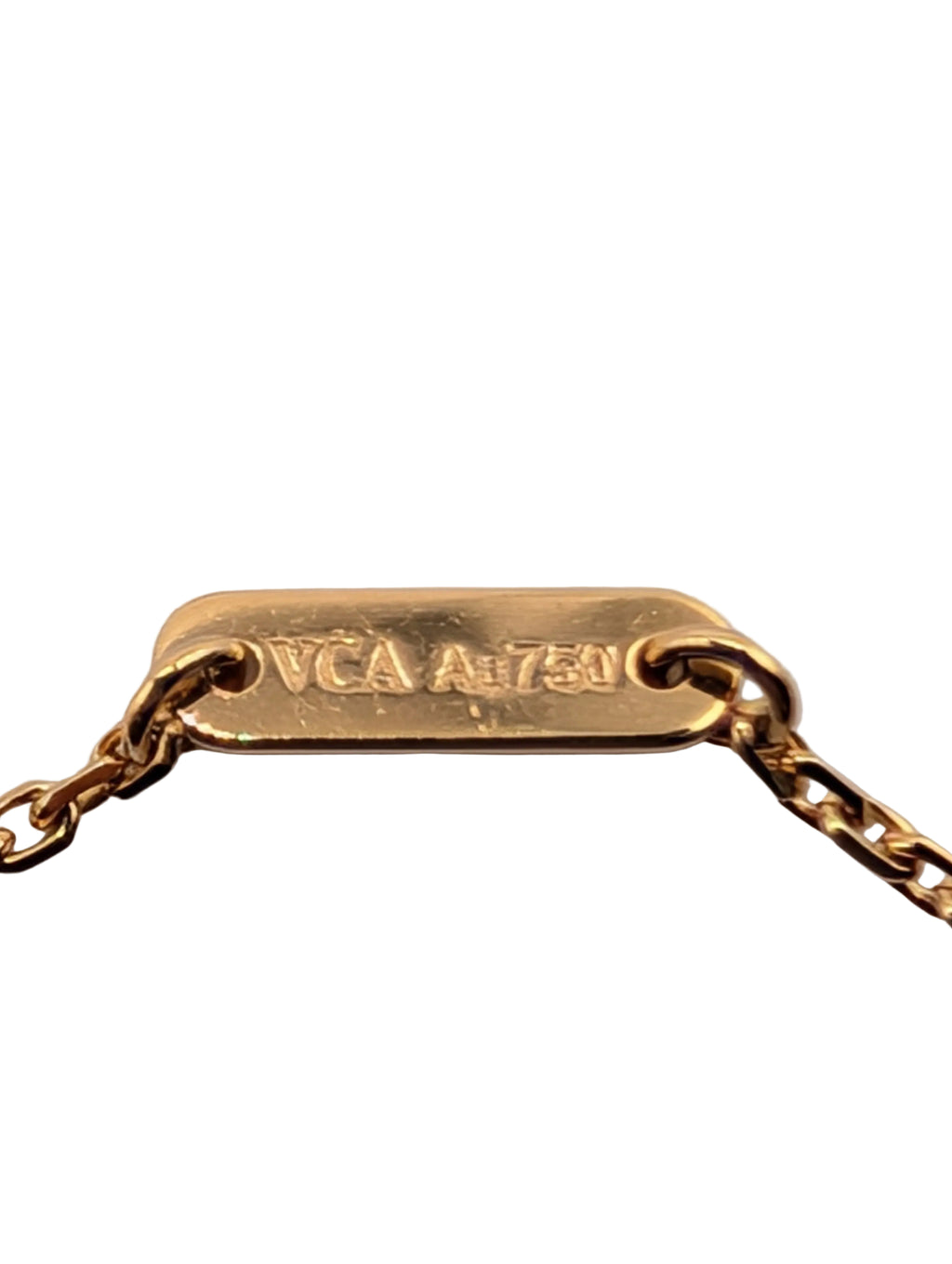 A close-up of a gold chain necklace with a rectangular gold tag engraved with 'VCA A 1750' on a light gray background.
